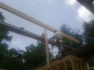 Carpenter setting a ridge beam over a new addition frame — Ice Dam Removal by Roofing Brothers in Manchaca