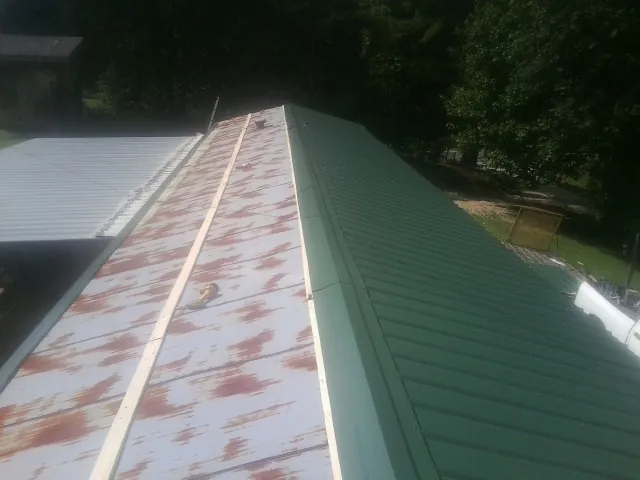 Old rusted panels beside newly installed green metal roofing — Wind Damage Roof Repair by Roofing Brothers in Manchaca