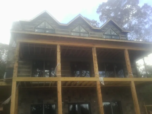 Dormers and porch framing on a large log home under construction — Roof Coating work by our crew in Manchaca