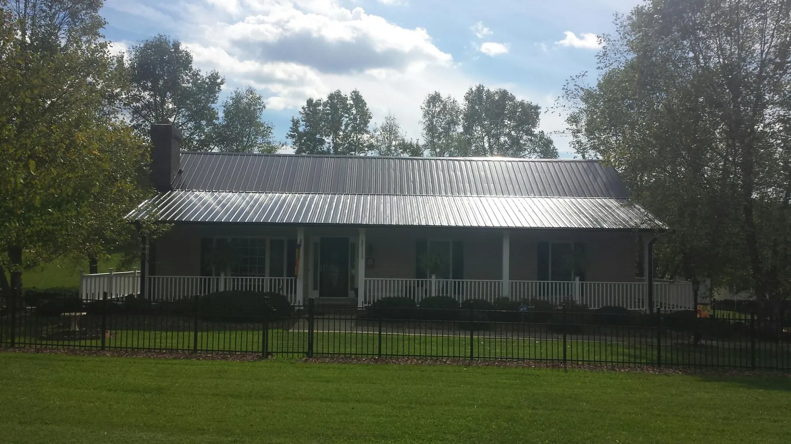 Gray metal roof on a brick ranch with a full width front porch — Gutter Guard Installation work by our crew in Manchaca