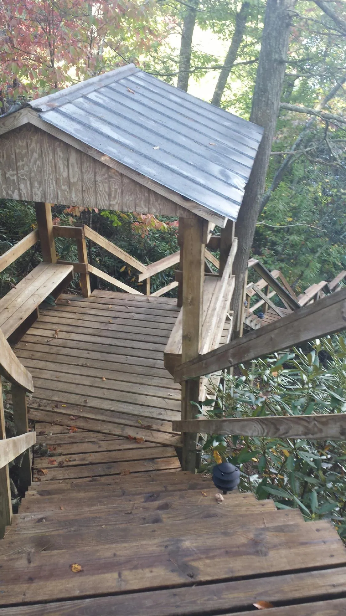 Metal roofed shelter over wooden steps on a wooded walkway — Skylight Repair & Installation work by our crew in Manchaca